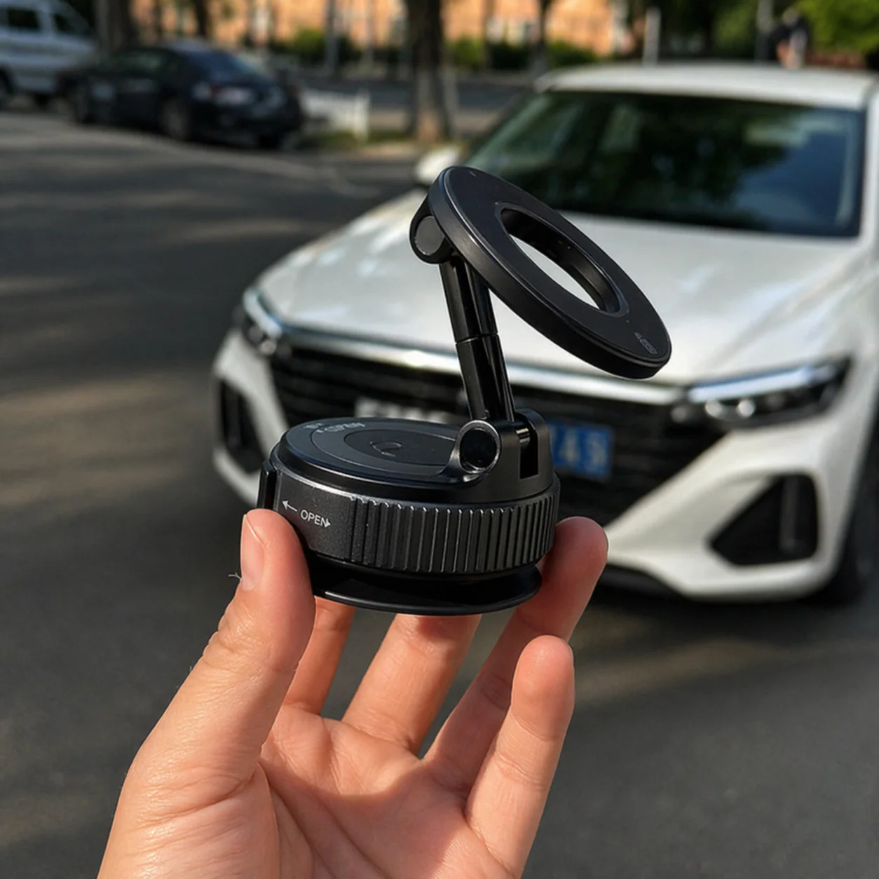 FlexMag mount held in hand in front of a white car